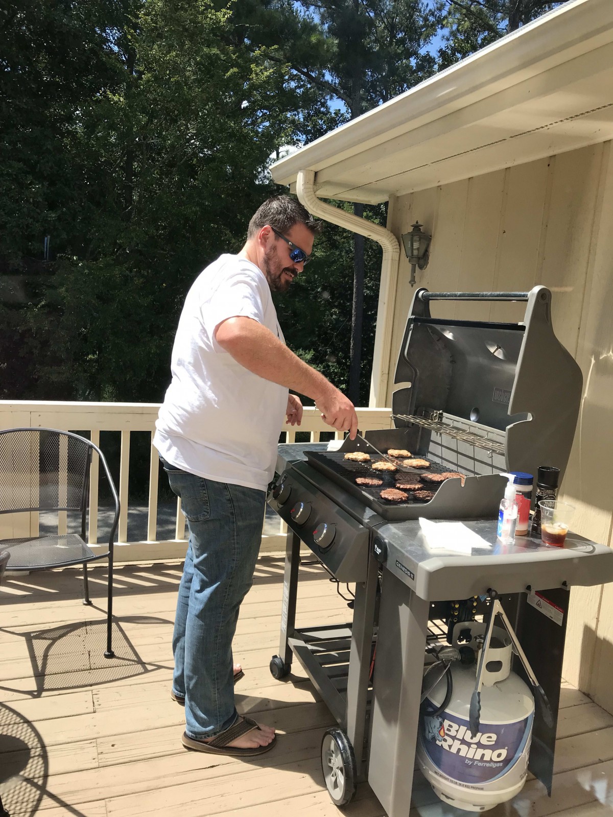 A man grills food on a barbecue on the patio.