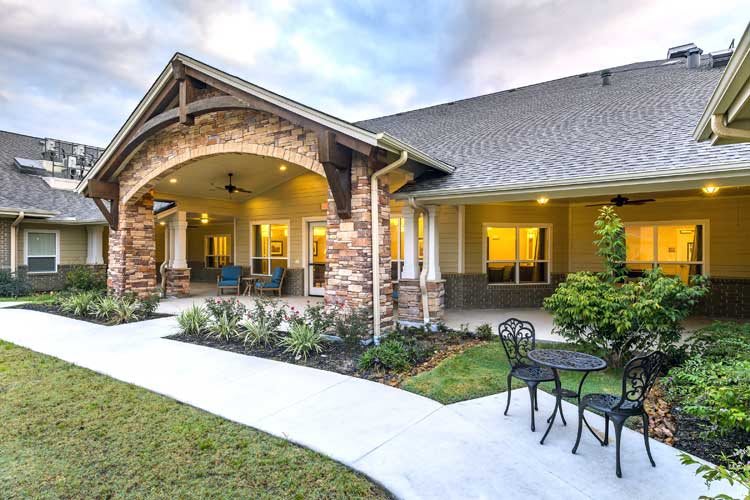 A beautiful house exterior featuring a landscaped path leading to a cozy patio with outdoor seating.