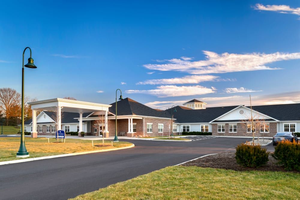 A modern building with a driveway under a blue sky with clouds.