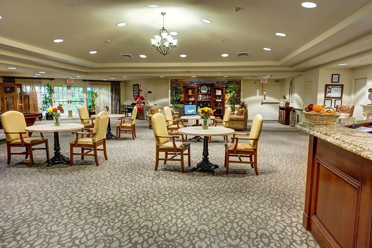 A spacious dining area with neatly arranged tables and chairs, featuring elegant lighting and decorative shelves on the wall.