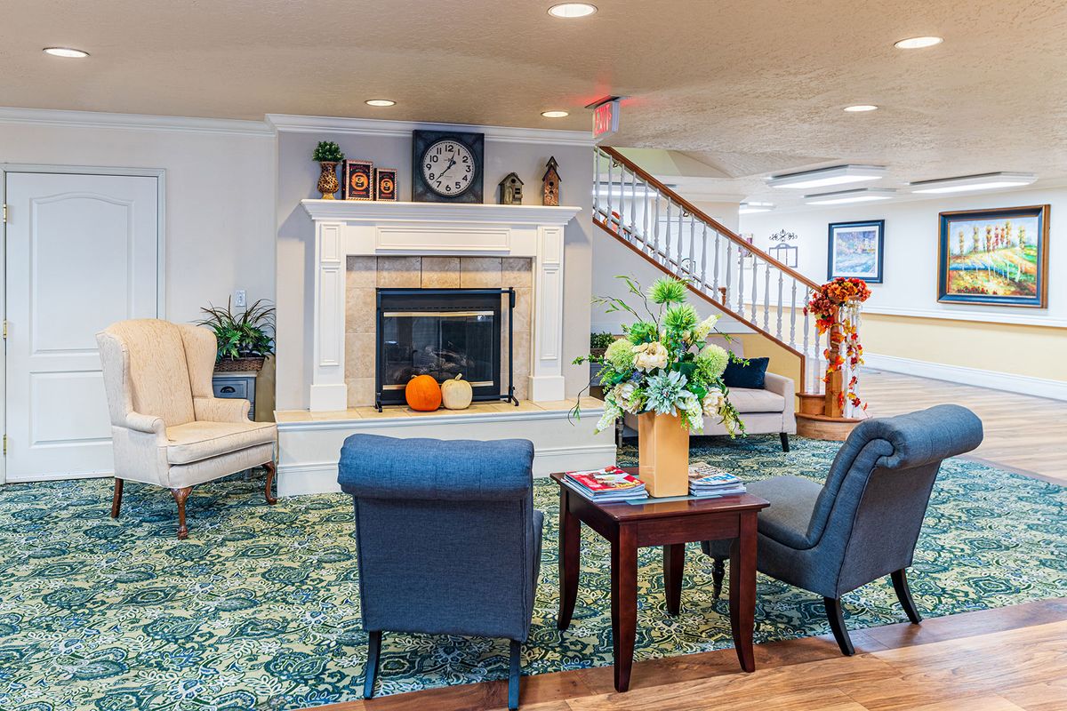 A cozy living room with a fireplace, elegant seating, and floral decor.