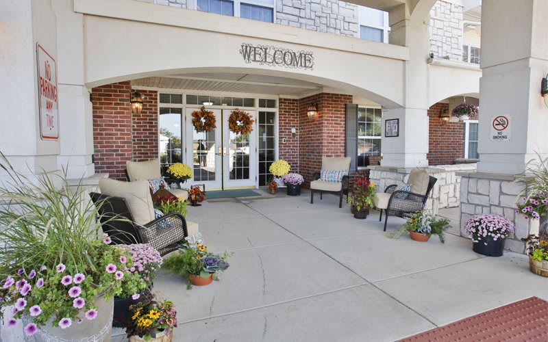 Front entrance with welcoming decor and outdoor seating surrounded by flowers.