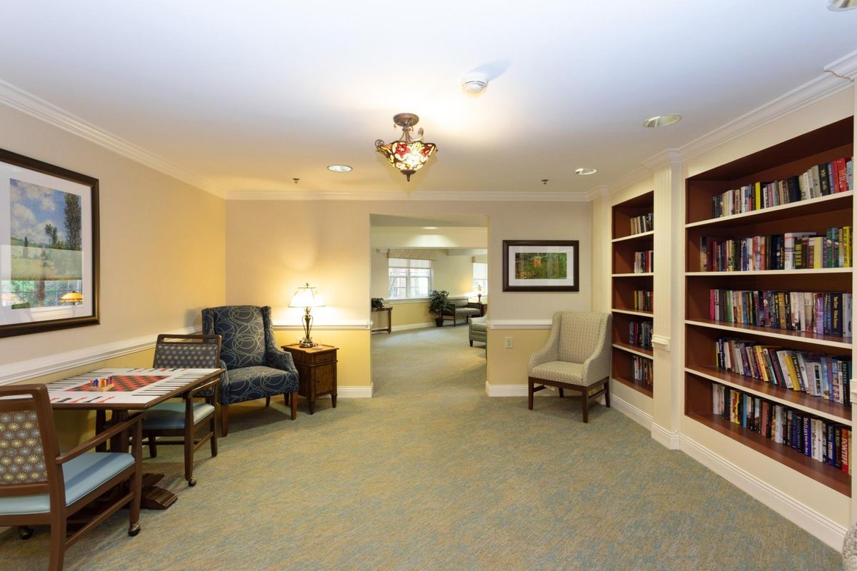A cozy living room area with comfortable seating, bookshelves, and soft lighting.