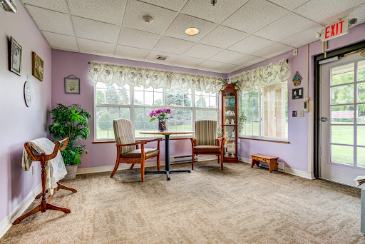 A cozy living space with purple walls and ample natural light, featuring comfortable rockers and decorative elements.
