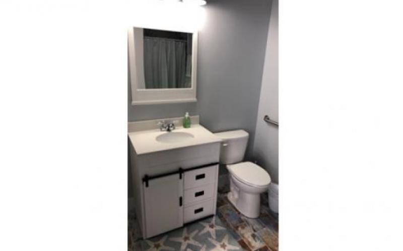 A modern bathroom with a vanity, sink, mirror, and toilet.