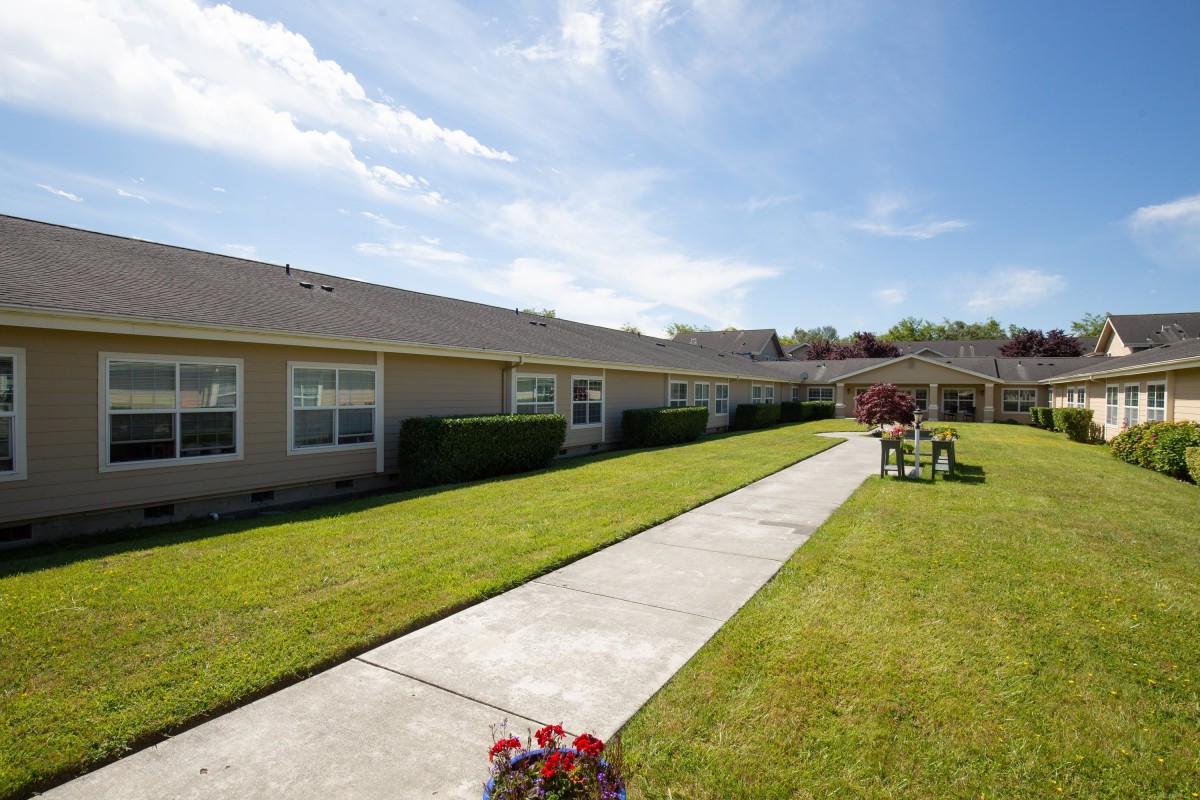 A single-story building with a well-maintained lawn and a sidewalk on a sunny day.