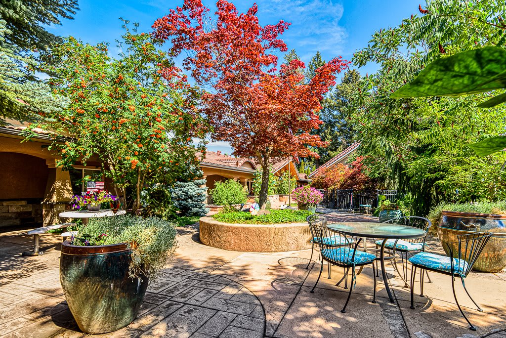 A beautifully landscaped garden patio with outdoor seating and colorful foliage.