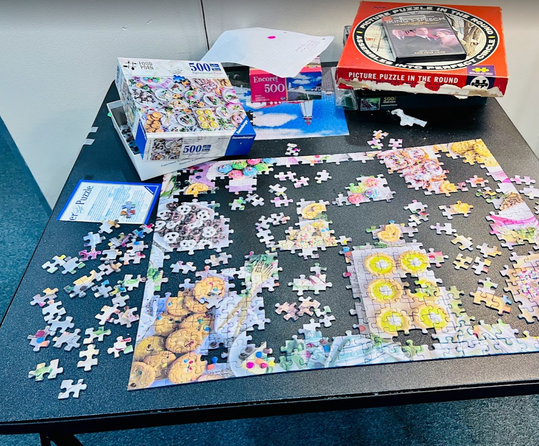 An incomplete jigsaw puzzle spread across a table, with pieces in progress.