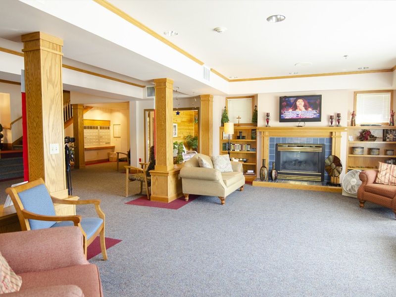 A cozy lobby area with comfortable seating, a fireplace, and a television.