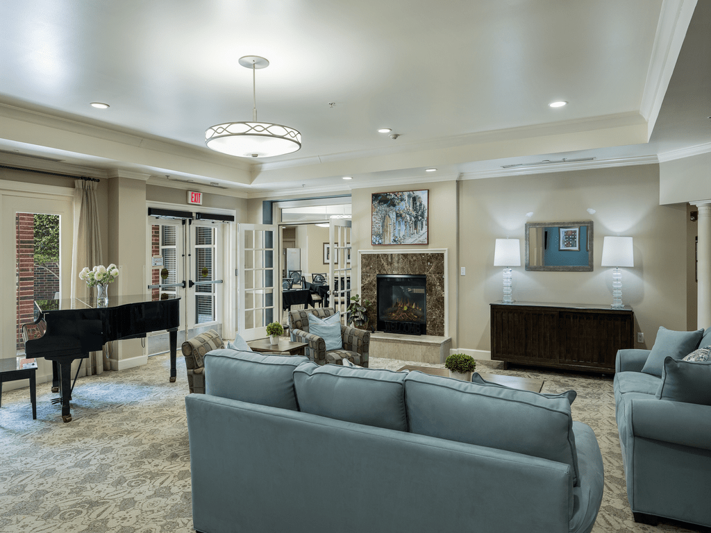 A modern living room with a comfortable sofa, elegant chandelier, and a fireplace.