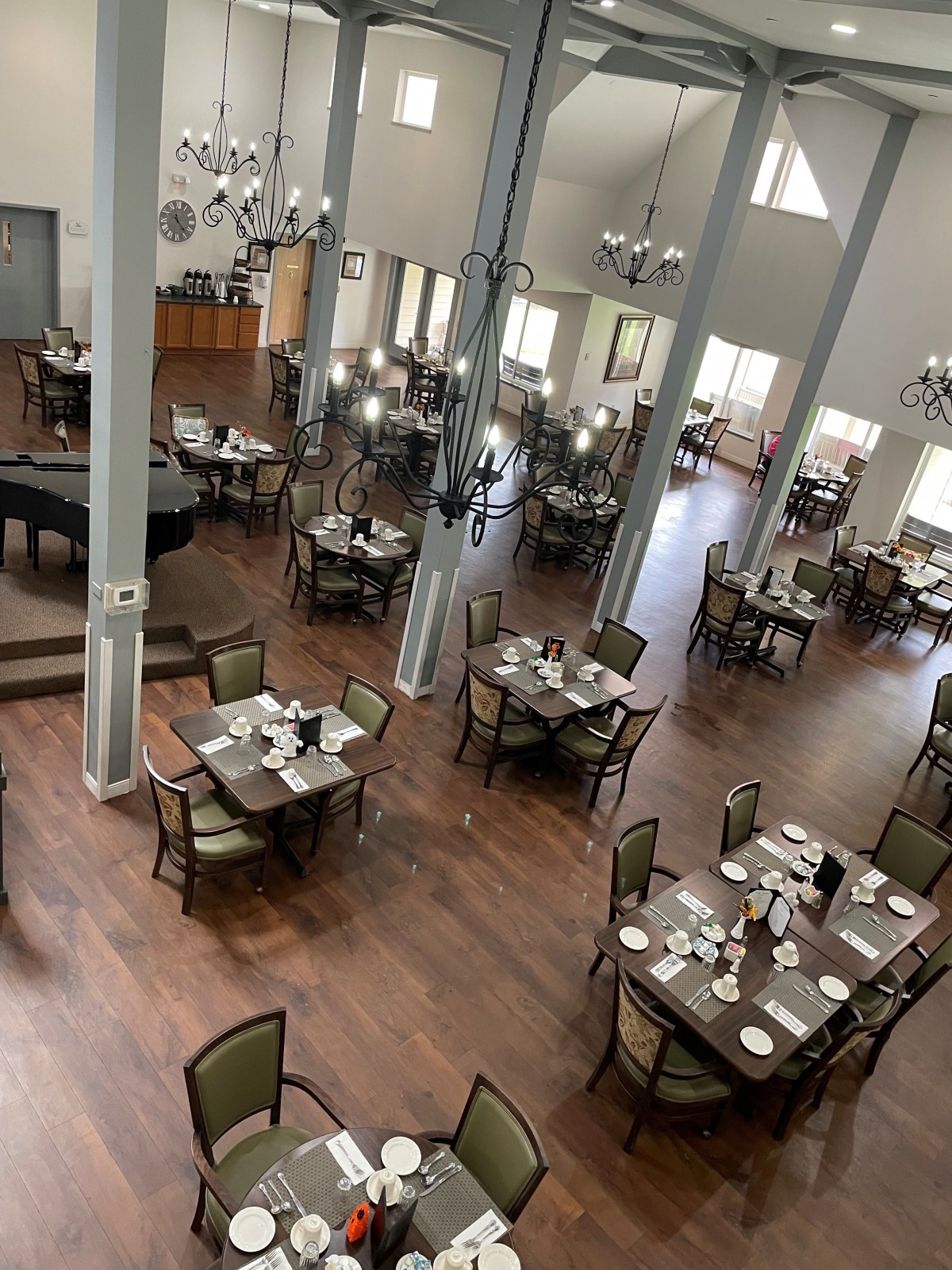 An elegant dining room with neatly arranged tables and a grand piano.