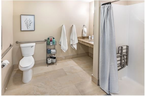 A clean and organized bathroom with a shower, toilet, sink, and storage rack.