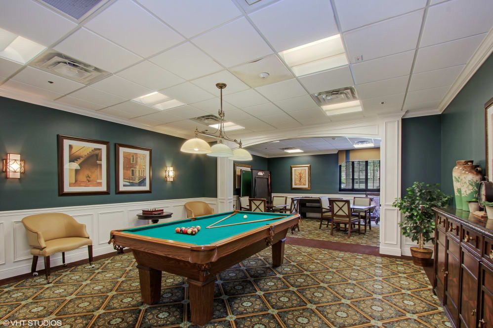 A cozy recreation room featuring a billiards table, ambient lighting, and seating areas.