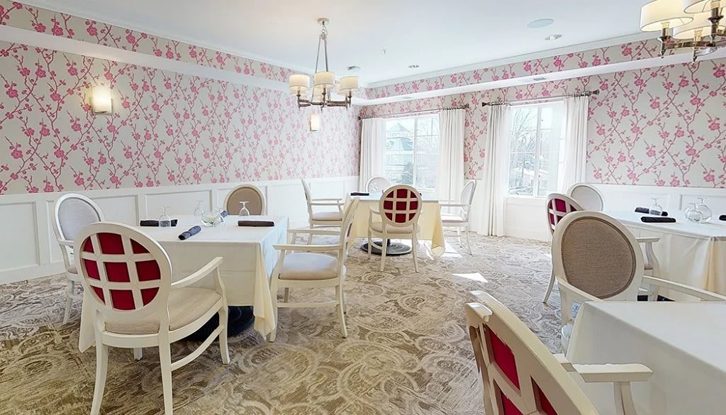 A well-lit dining room with elegant furnishings and floral wallpaper.