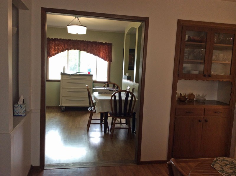 A cozy dining room with a table and chairs, featuring a large window with curtains.