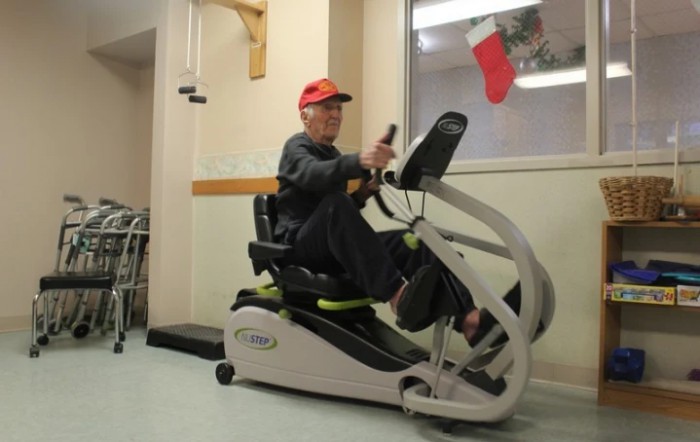 A senior person exercises on a recumbent bike indoors, focusing on health and wellness.