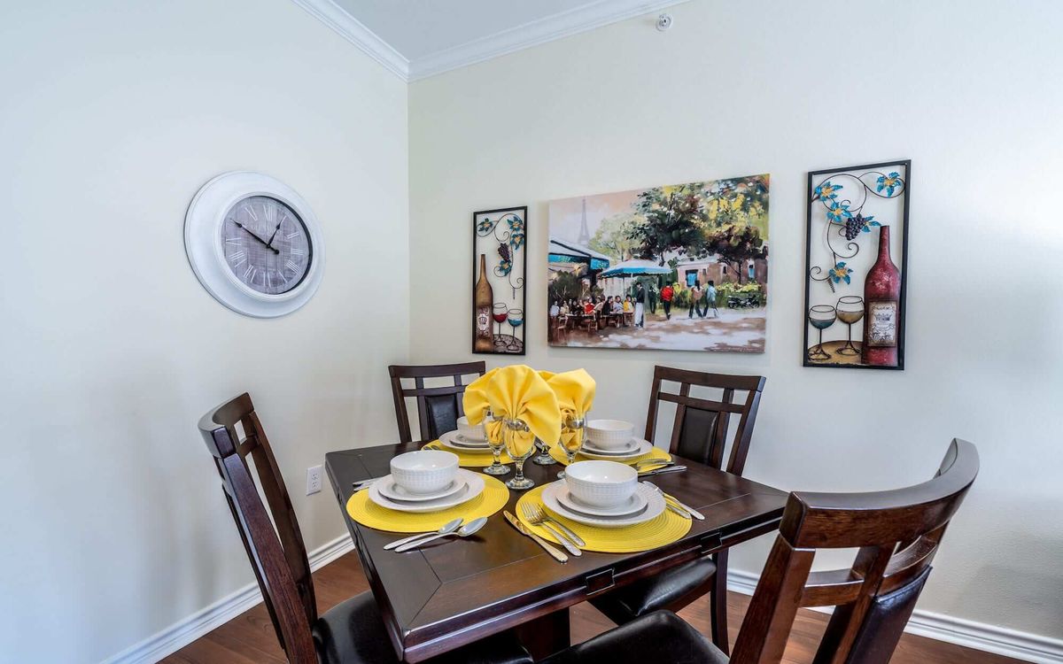 A cozy dining room with a set table featuring yellow accents and wall art.
