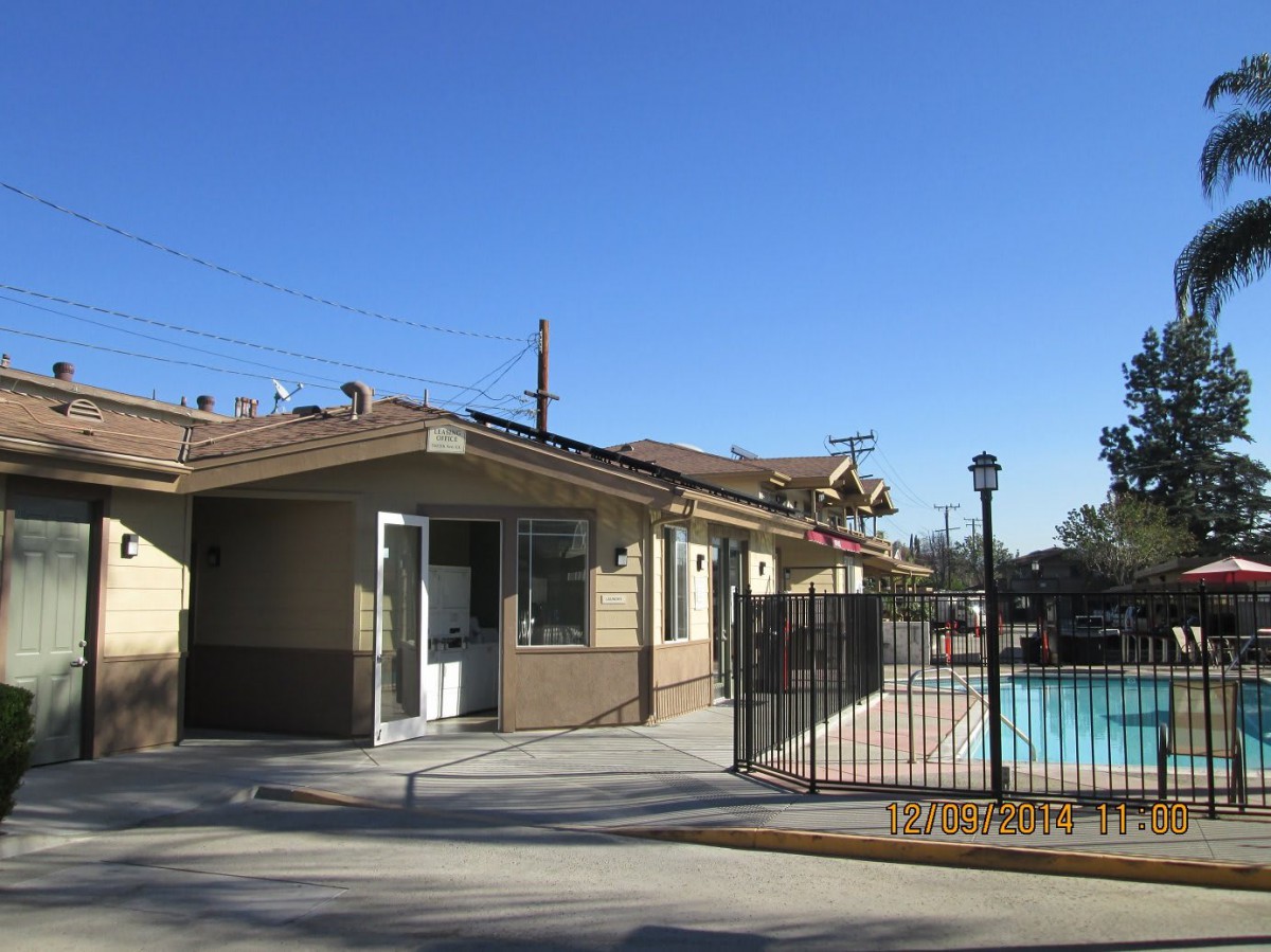 A small building next to a fenced outdoor pool under a clear blue sky.