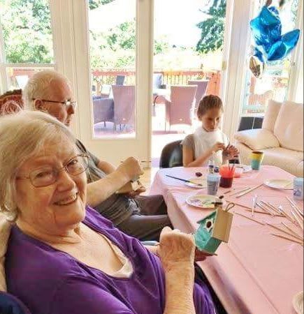 An elderly woman and a child happily engage in painting activities at a family gathering.