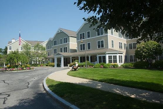 A large residential building with a well-maintained lawn and surrounding greenery on a sunny day.