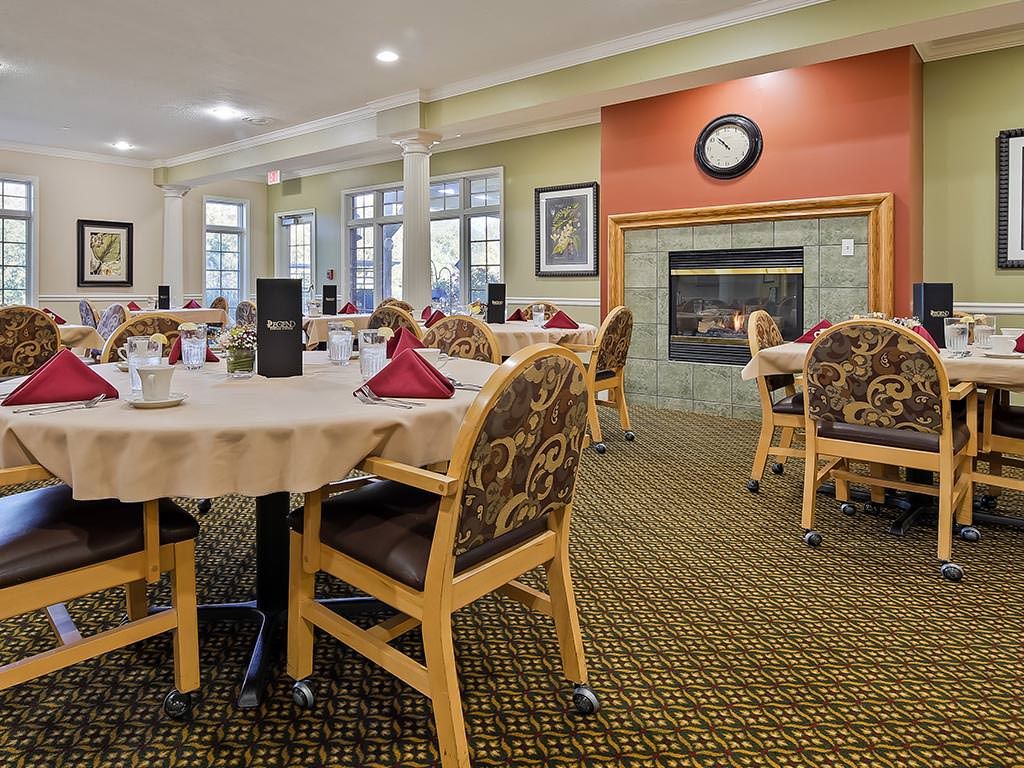 A spacious dining room with neatly arranged tables and chairs, featuring a fireplace and decorative elements.
