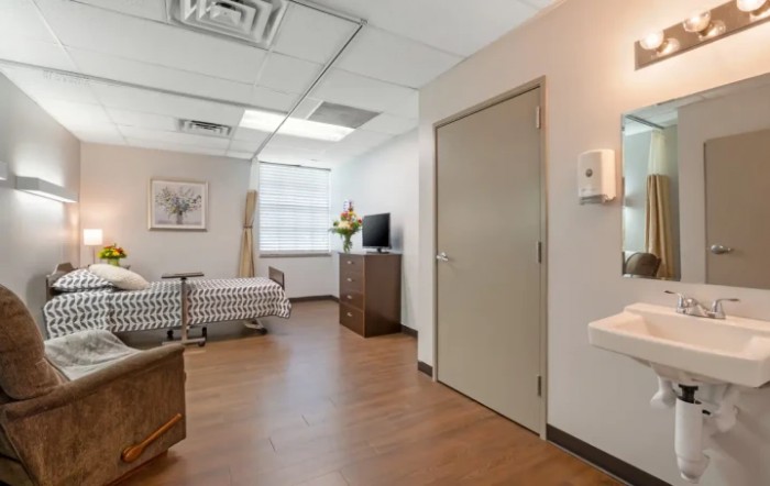A clean and modern hospital room with a bed and television.