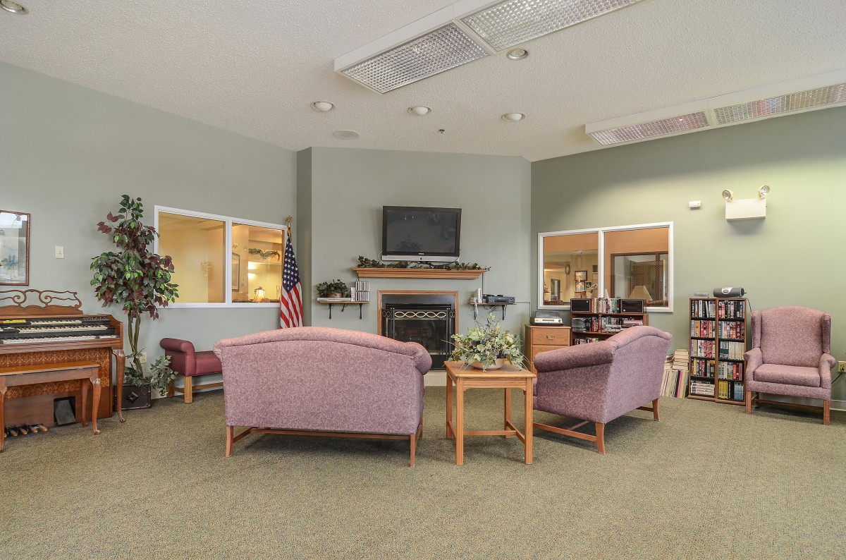 A cozy waiting room with sofas, a fireplace, and indoor plants.