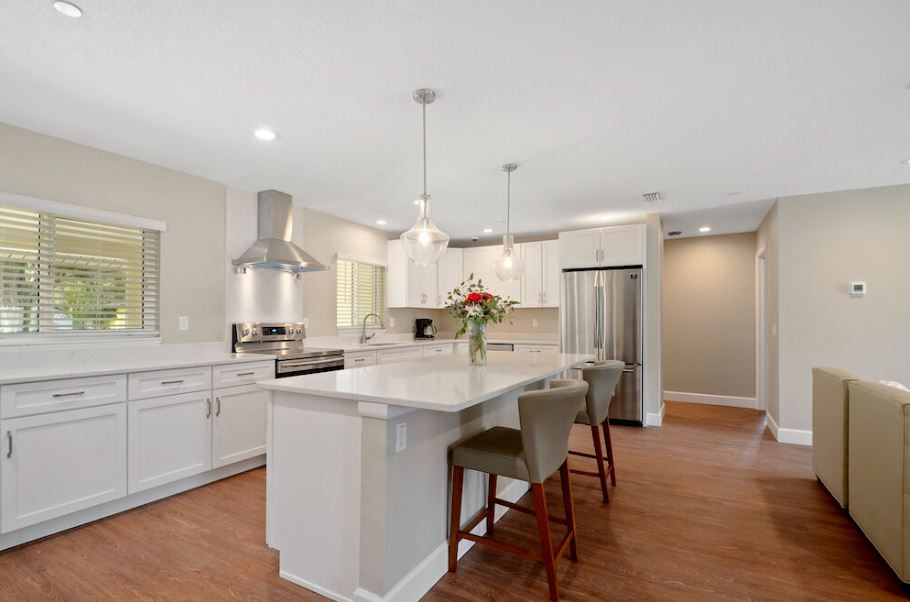 A modern kitchen featuring an island with bar stools, pendant lighting, and stainless steel appliances.