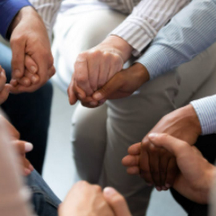 A group of people holding hands in a circle, symbolizing unity and support.