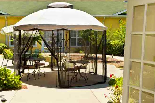 An outdoor patio area featuring a gazebo with furniture and an umbrella.