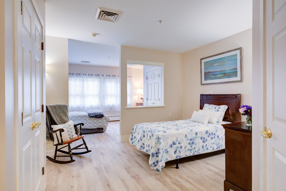 A cozy bedroom with a bed, rocking chair, and wooden floors.