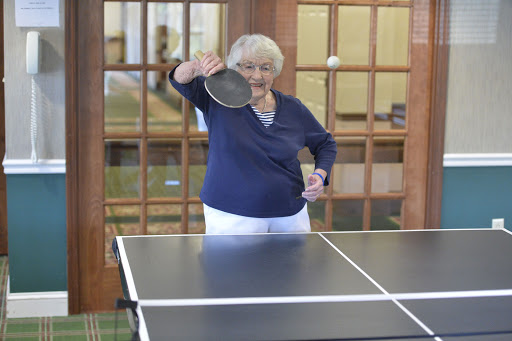 An older woman gearing up to play table tennis.