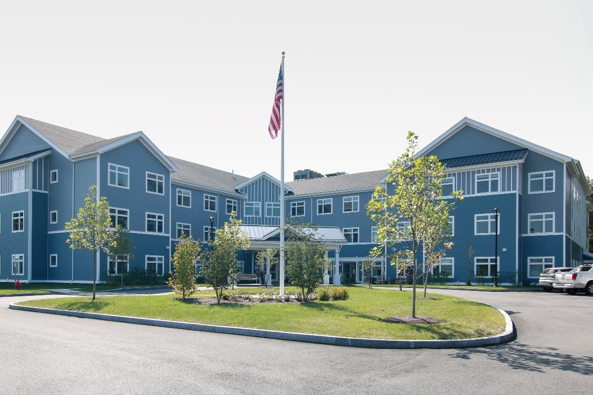A multi-story residential building with a flagpole and landscaped surroundings.
