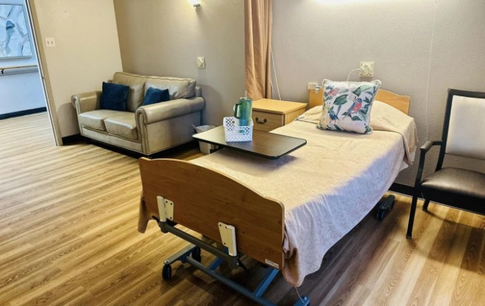 A well-furnished hospital room with a bed and a sofa, featuring a clean and accessible environment.