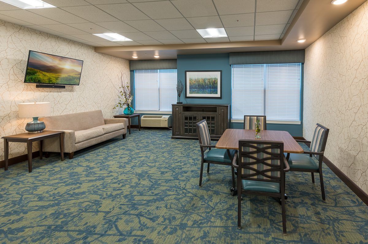 A spacious waiting room with a sofa, table, chairs, and decorative artwork.