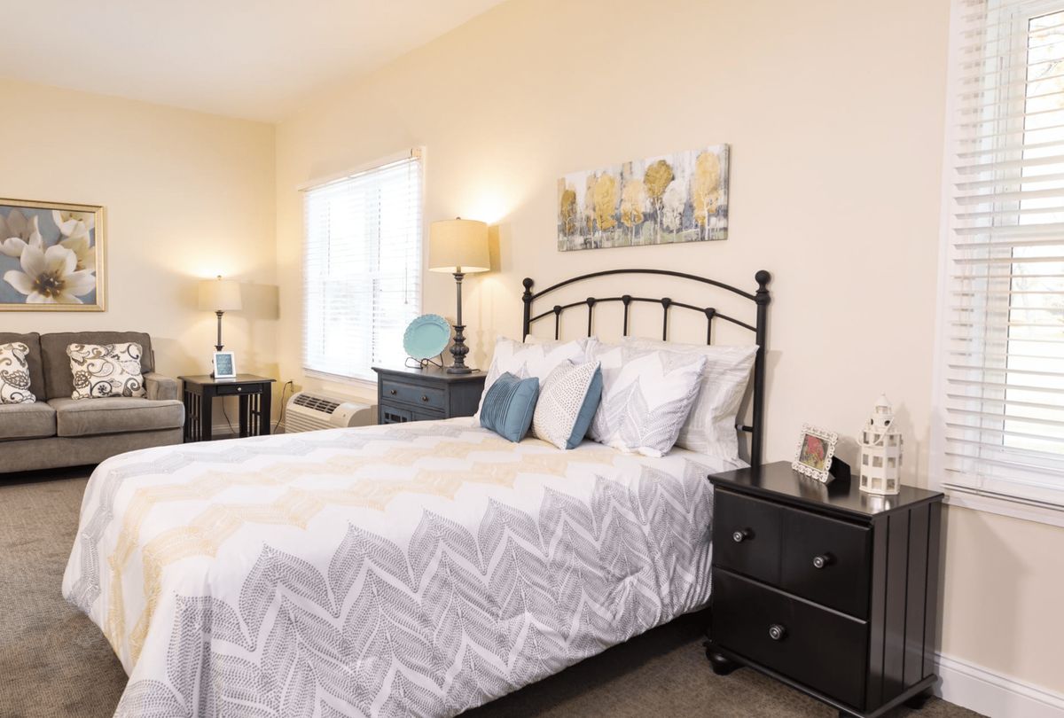 A cozy bedroom with a neatly made bed, decorative pillows, and stylish lamps on nightstands.