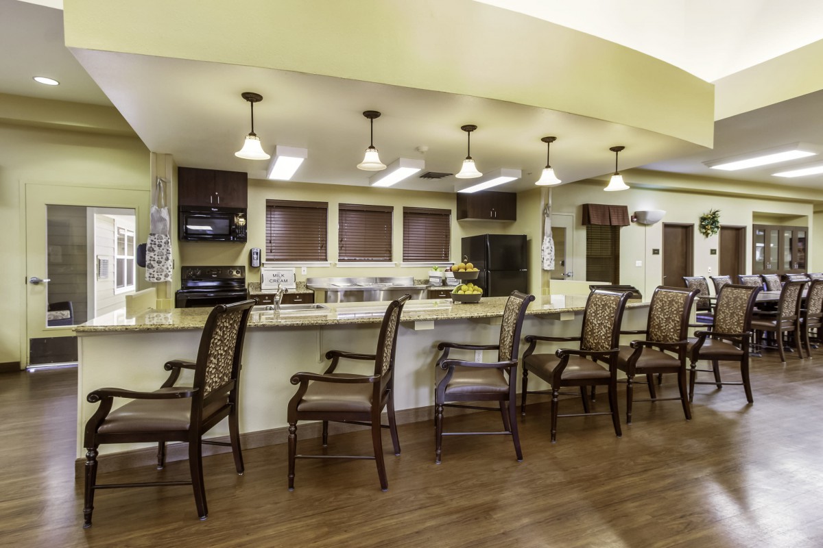 A modern kitchen and dining area with a counter, chairs, and overhead lighting.