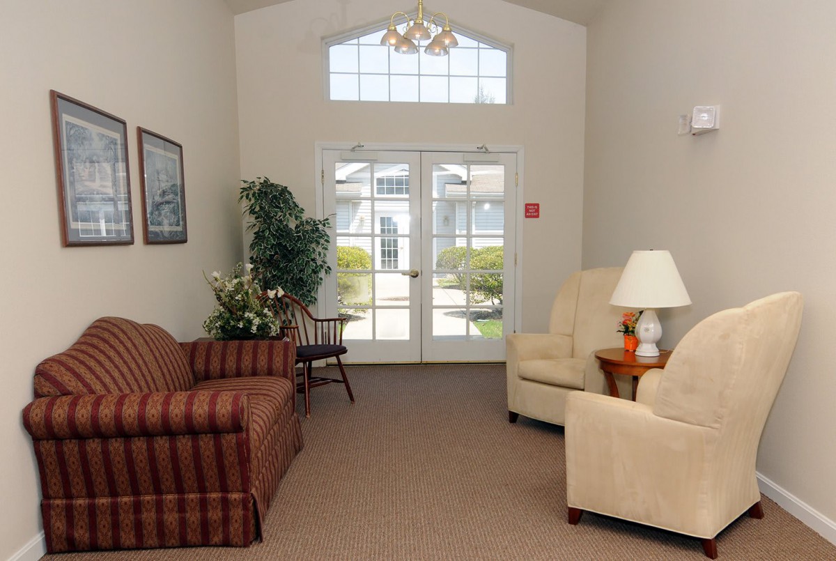 A cozy living room with a sofa, armchairs, and large windows.