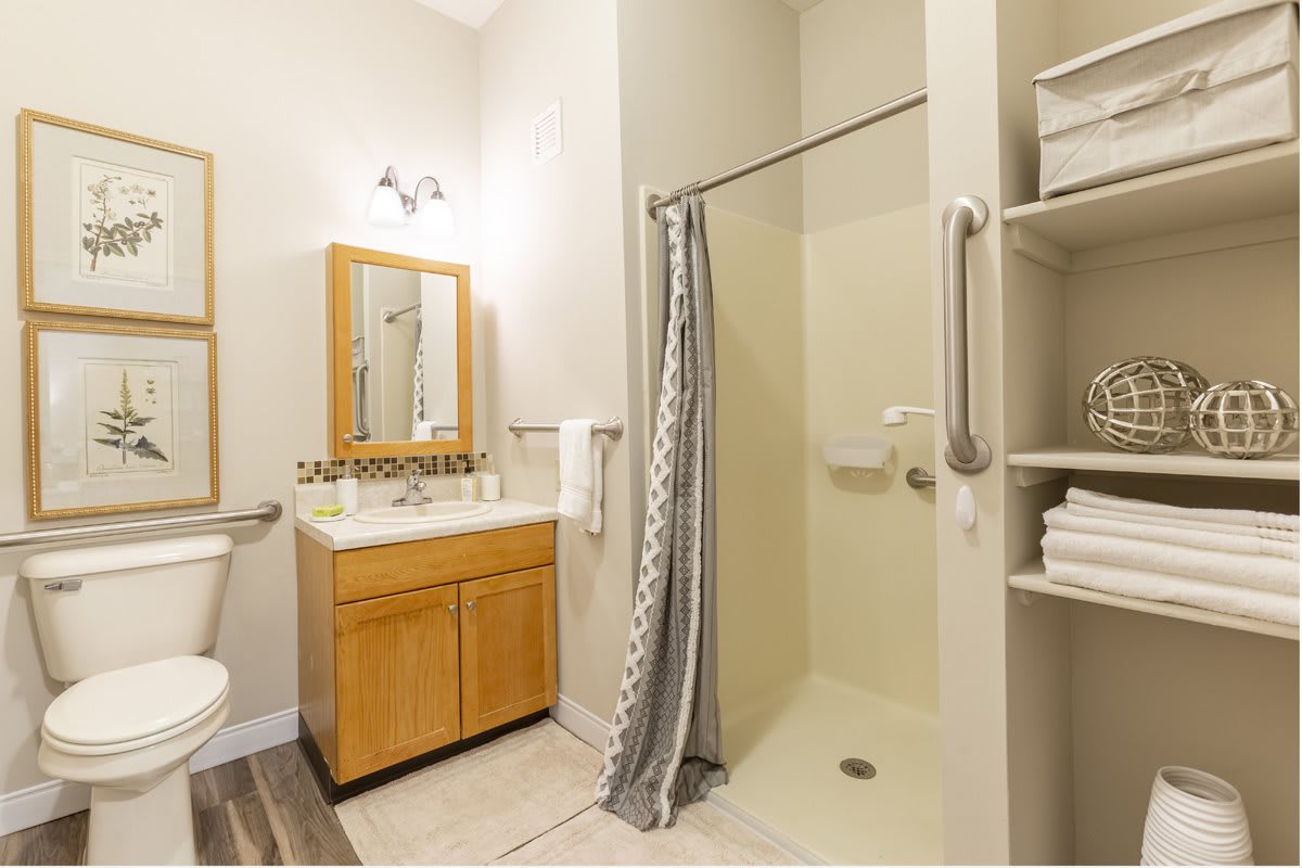 A clean and well-organized bathroom with a shower, vanity, and mirror.
