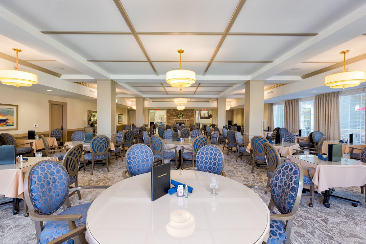 An elegantly decorated dining area with multiple tables and chairs arranged in a spacious, well-lit room.