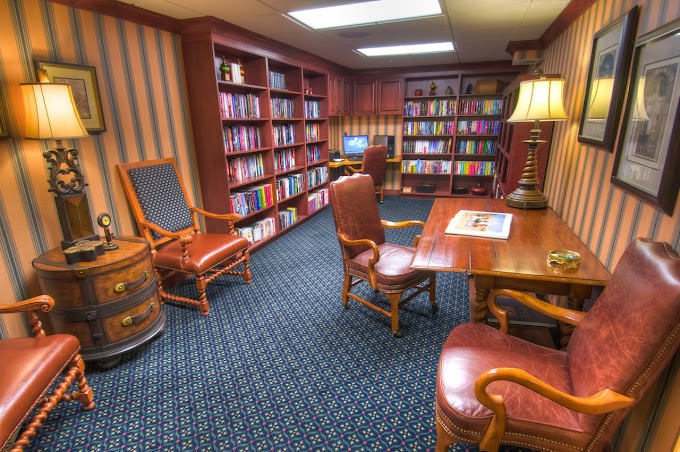 A cozy library room with bookshelves, a reading desk, and comfortable chairs.