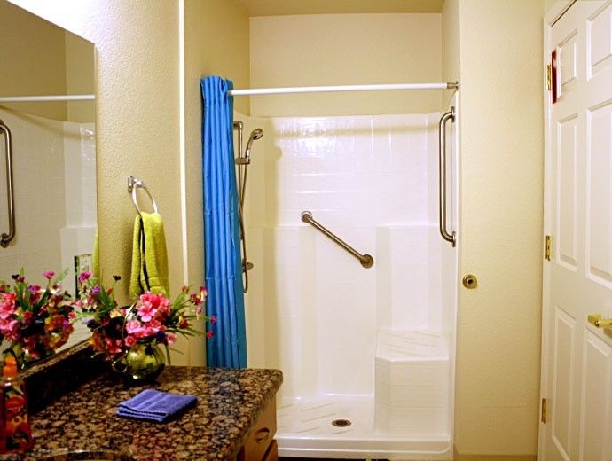 A bathroom interior featuring a shower with a blue curtain and grab bar.
