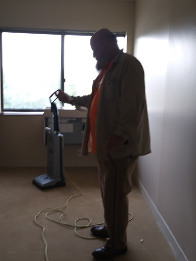 A person preparing to use a vacuum cleaner in an empty room.