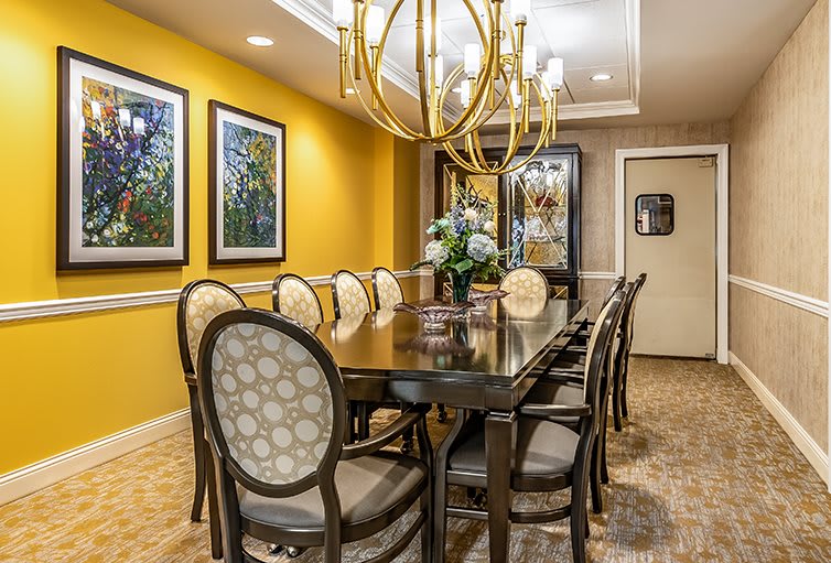 A well-decorated dining room with a large table, elegant chairs, and a striking chandelier.
