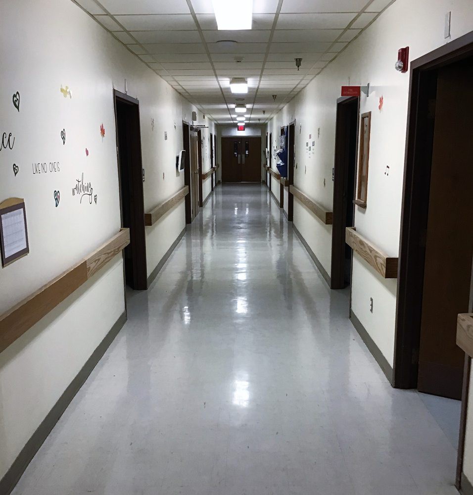 A quiet hospital corridor with rooms along both sides.
