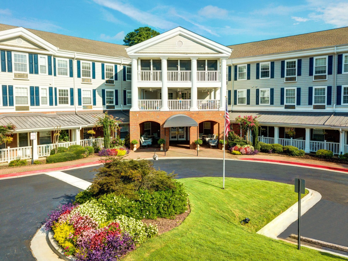 A well-maintained residential building with a landscaped entrance and vibrant flowerbeds under a clear sky.