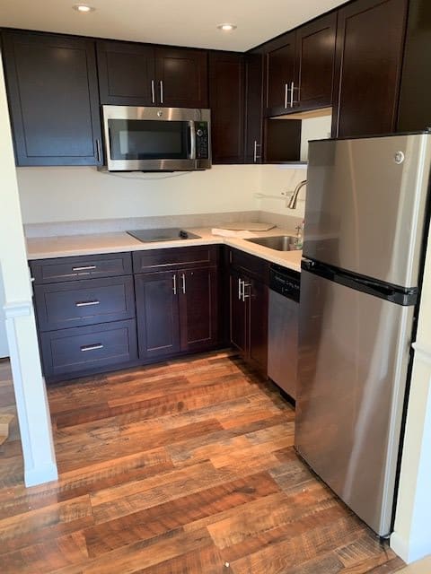 Modern kitchen with stainless steel appliances and dark cabinets.