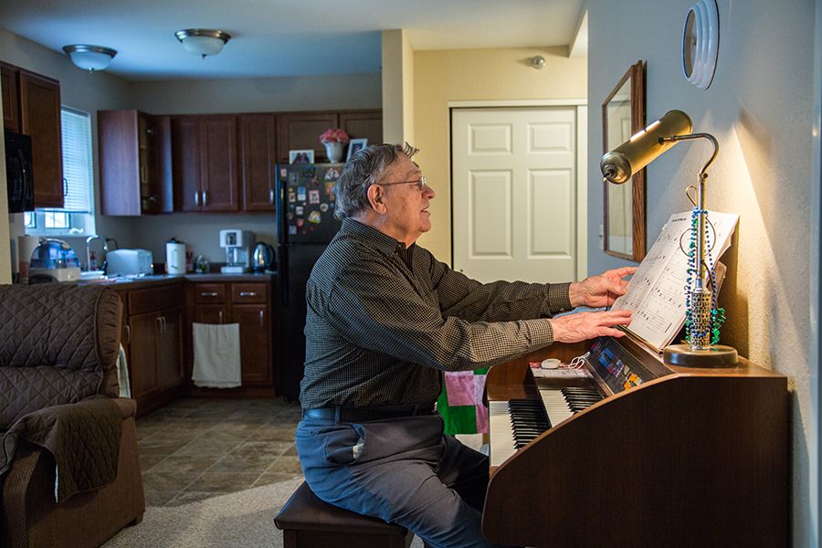 An older man playing the piano in his home.