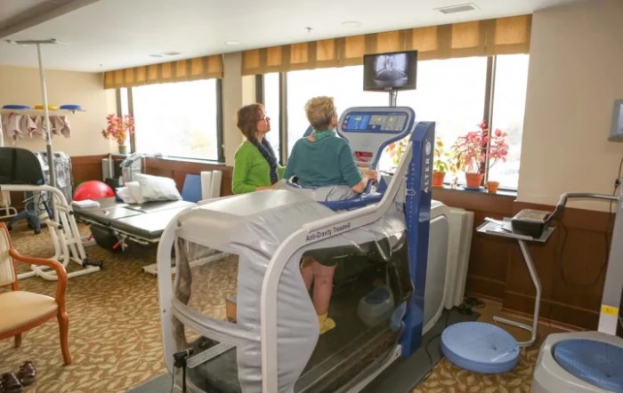 A person using an anti-gravity treadmill under the supervision of a therapist in a rehabilitation clinic.