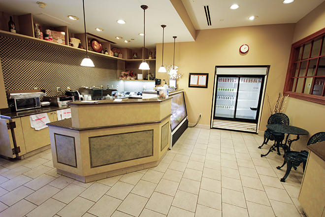 An empty coffee shop interior with a counter, display case, and refrigerator.
